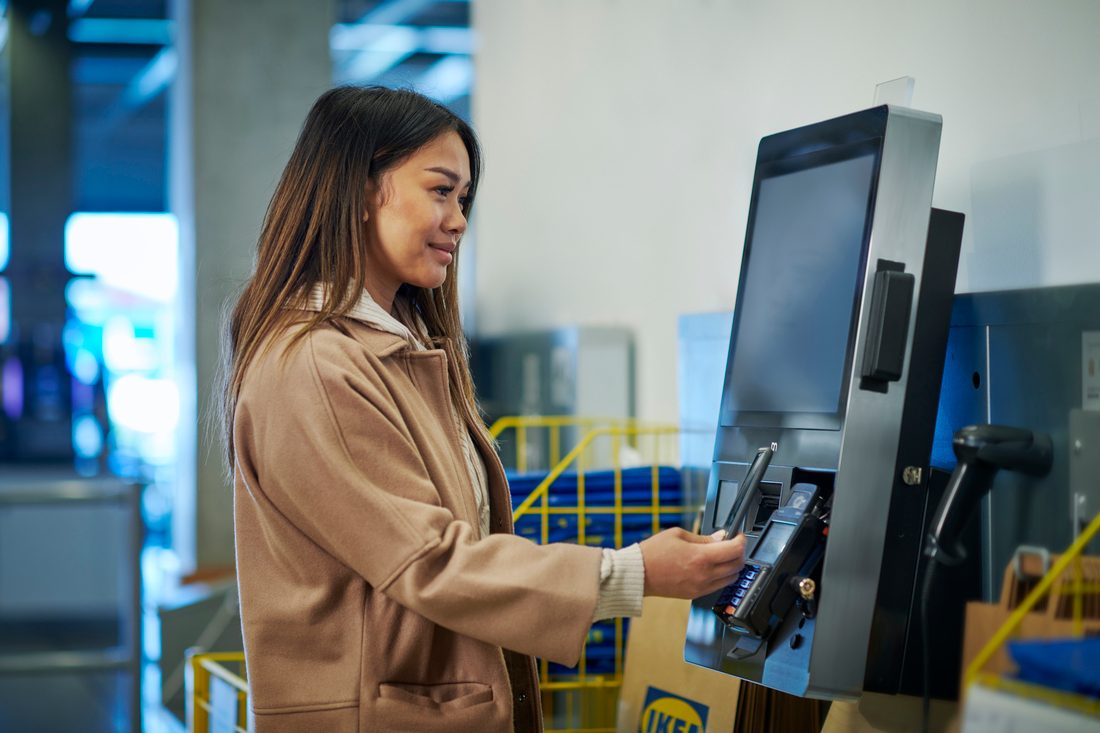 A customer using a handheld scanner at an IKEA self-checkout till.